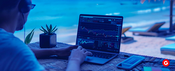 A man sitting by the shore with a laptop, participating in part time forex trading.