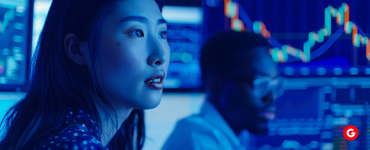 A woman analyzing stock market graphs on a screen.