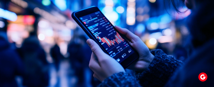 A person examines a smartphone displaying a stock market graph, indicating financial trends and data analysis.