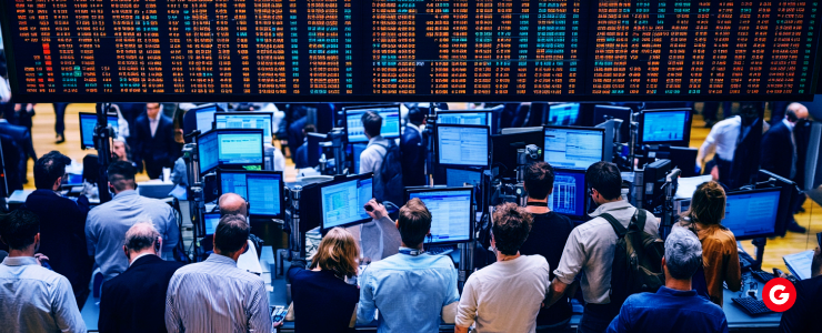 Several people stand before a large screen, surrounded by multiple smaller screens, likely analyzing information together.
